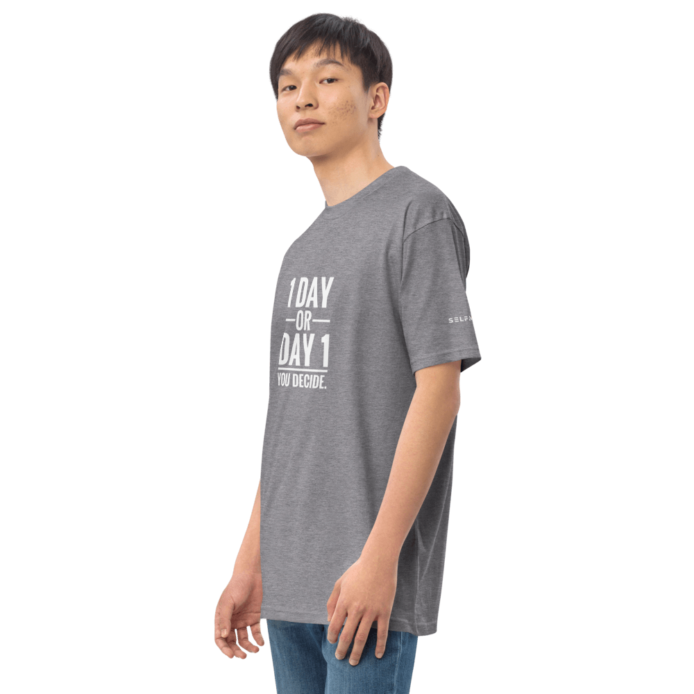 Model wearing a grey tee with motivational text: '1 DAY OR DAY 1. YOU DECIDE.' Perfect for casual outfits.