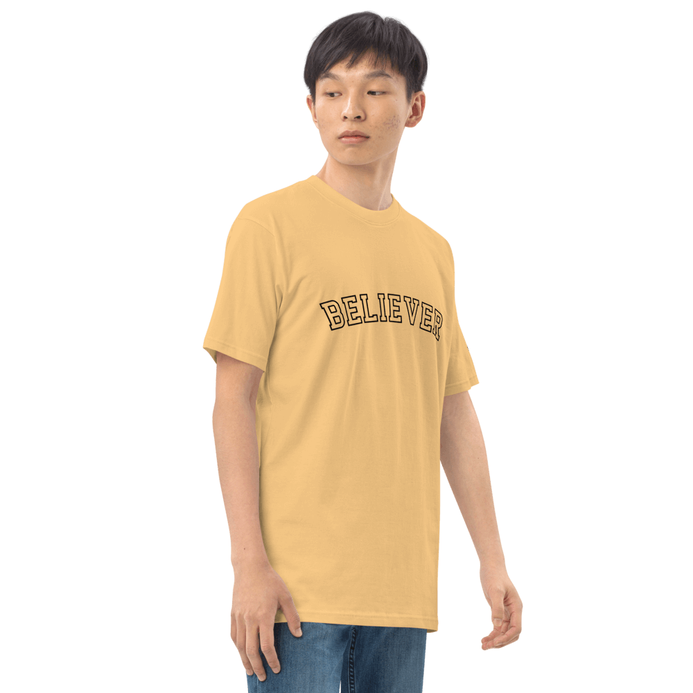 Model wearing a soft yellow essential tee with 'BELIEVER' print, made from premium organic cotton for a stylish look.